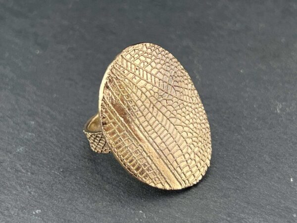 Gold textured ring with an oval face and intricate pattern.