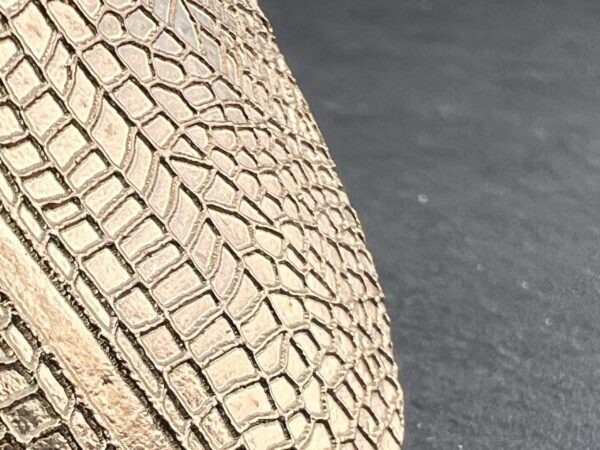Close-up of a textured beige woven handbag on a gray surface.