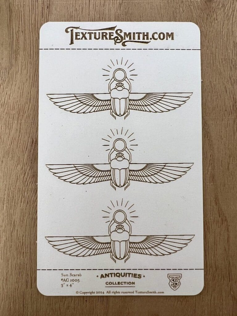 Three hand-drawn Egyptian scarab beetle designs with wings and radiant circles above.
