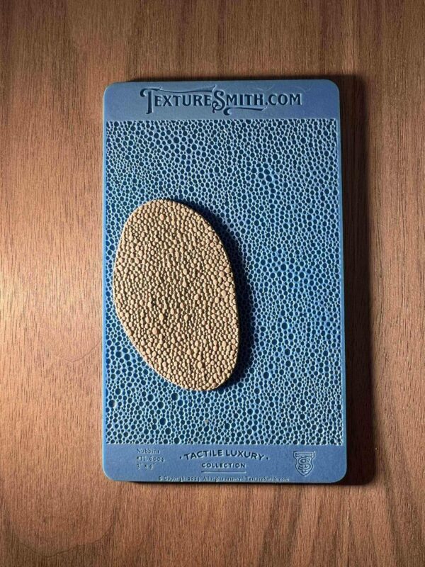 A textured blue card with an oval beige stone attached.