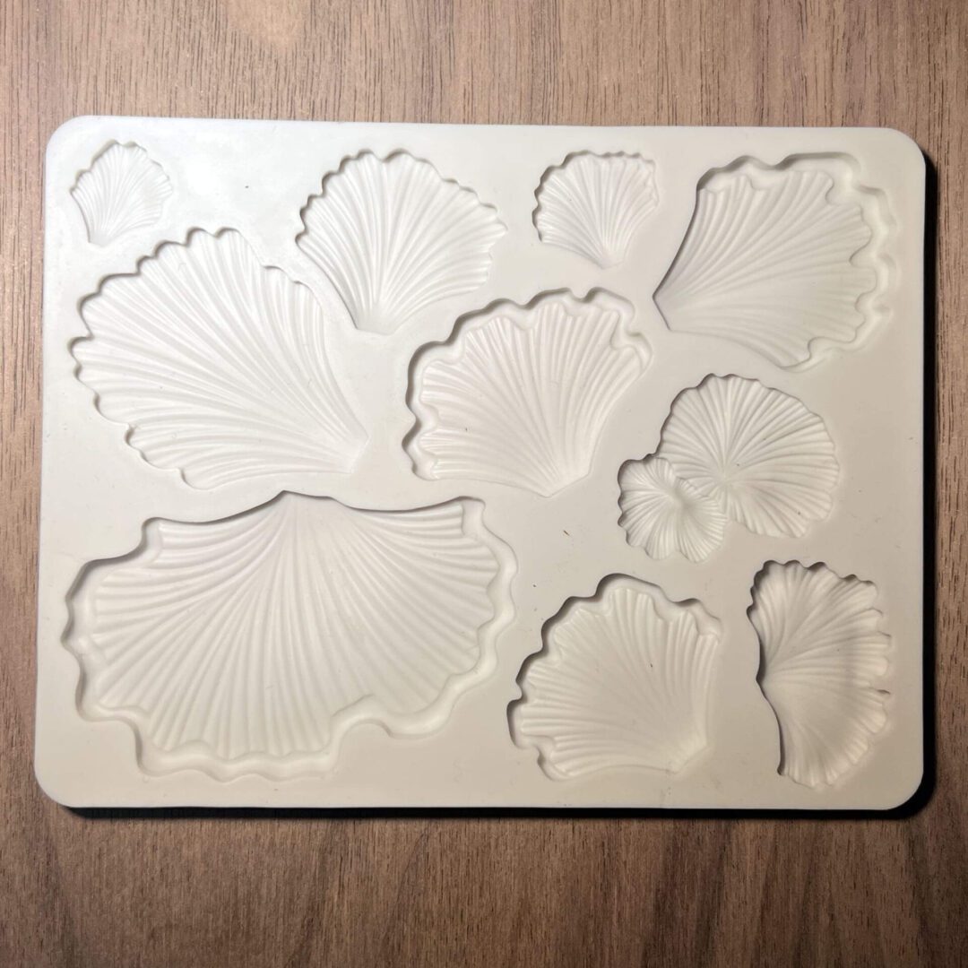 White silicone mold with various leaf shapes on a wooden surface.