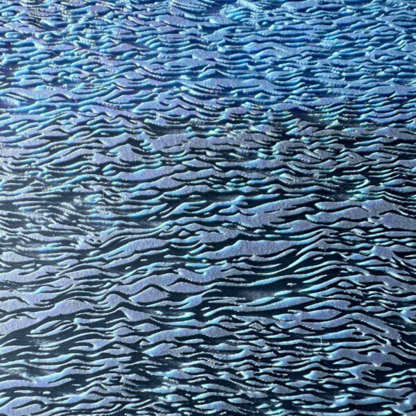 Close-up of textured water surface with ripples reflecting blue hues.