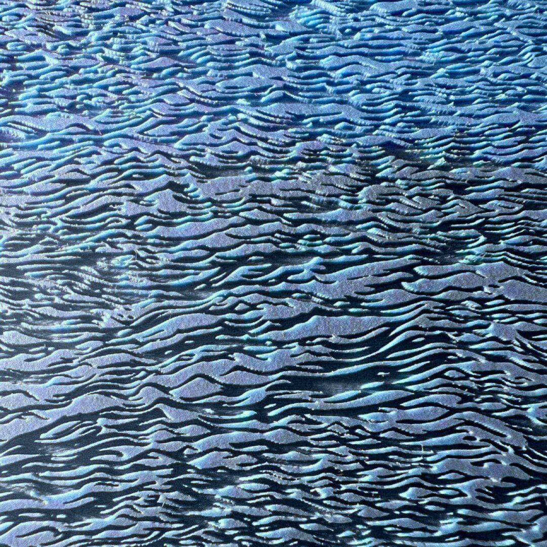 Close-up of textured water surface with ripples reflecting blue hues.