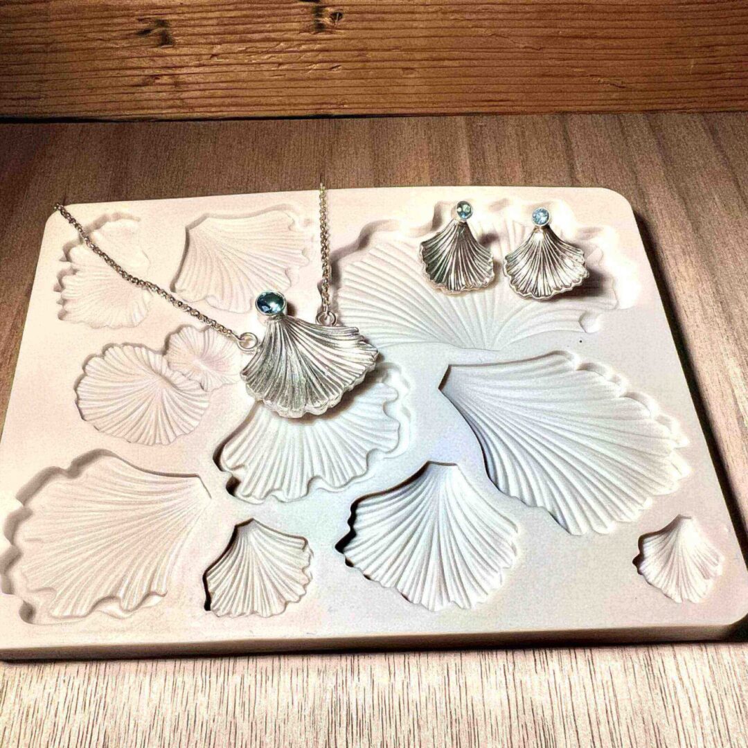 White plaster molds of various seashell shapes on a wooden table.
