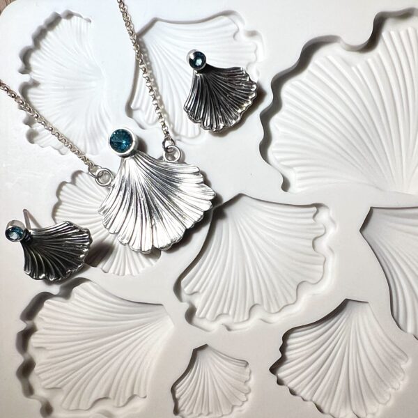 Elegant shell-shaped jewelry and matching white ceramic plates.