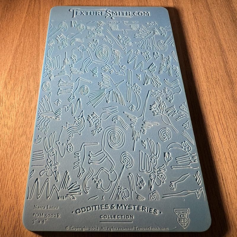 Embossed blue card with detailed floral and bird patterns on wooden surface.