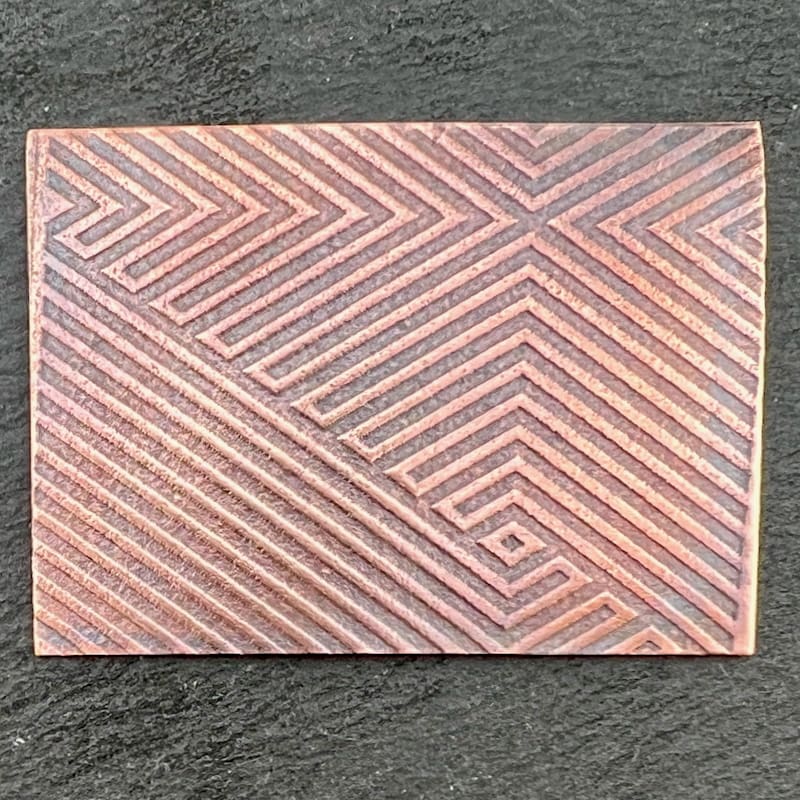 Rectangular tile with geometric line patterns in muted tones.