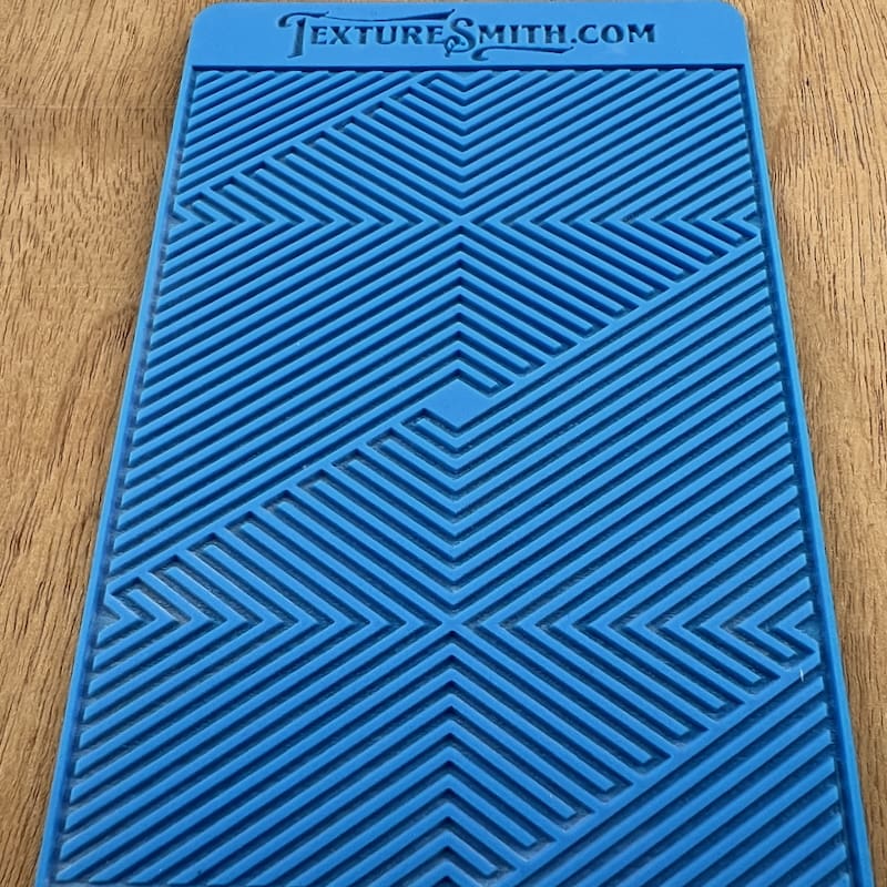 Blue textured mat with geometric patterns on a wooden surface.