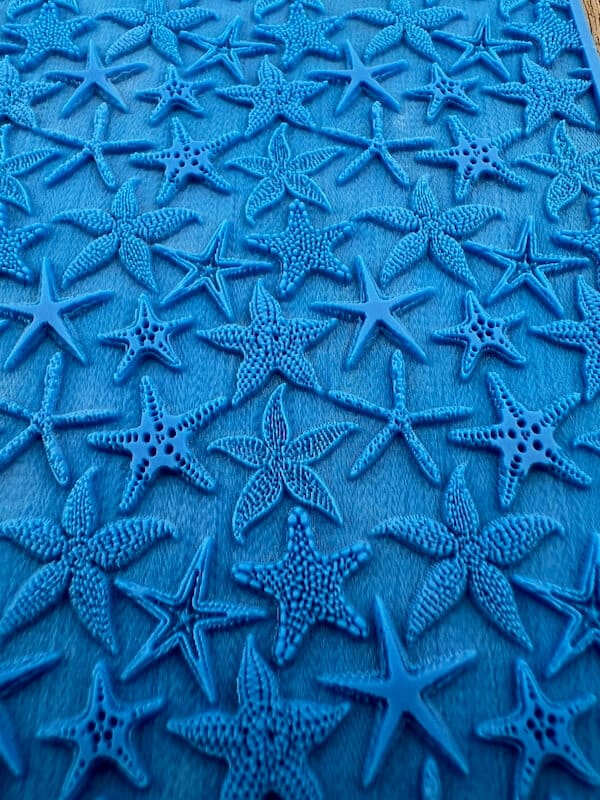 Close-up of blue fabric with starfish embroidery.