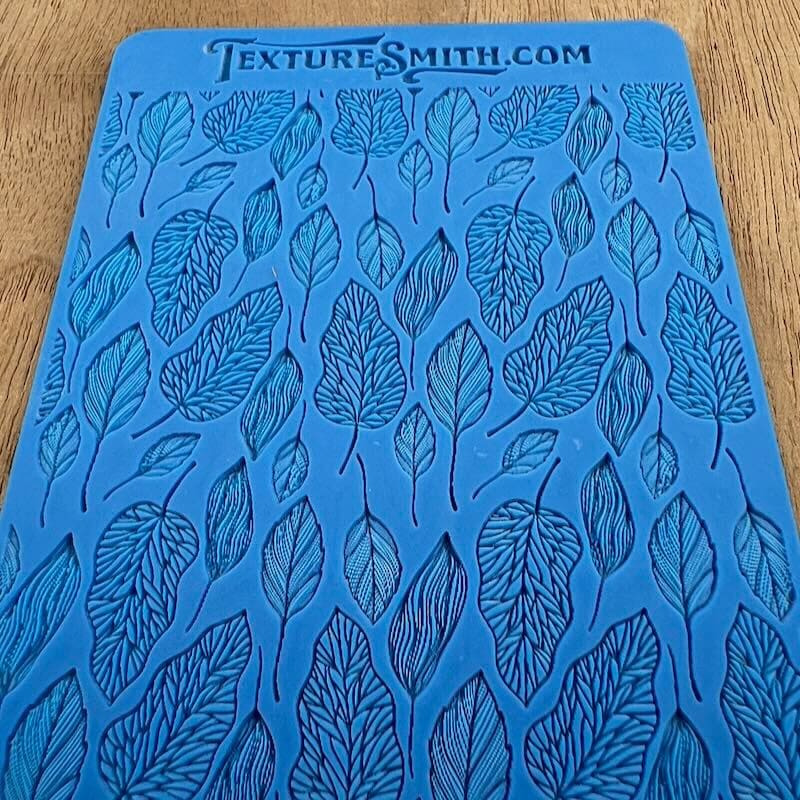Blue textile with leaf patterns and text at the top.