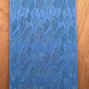 Blue notebook with a leaf pattern on a wooden surface.