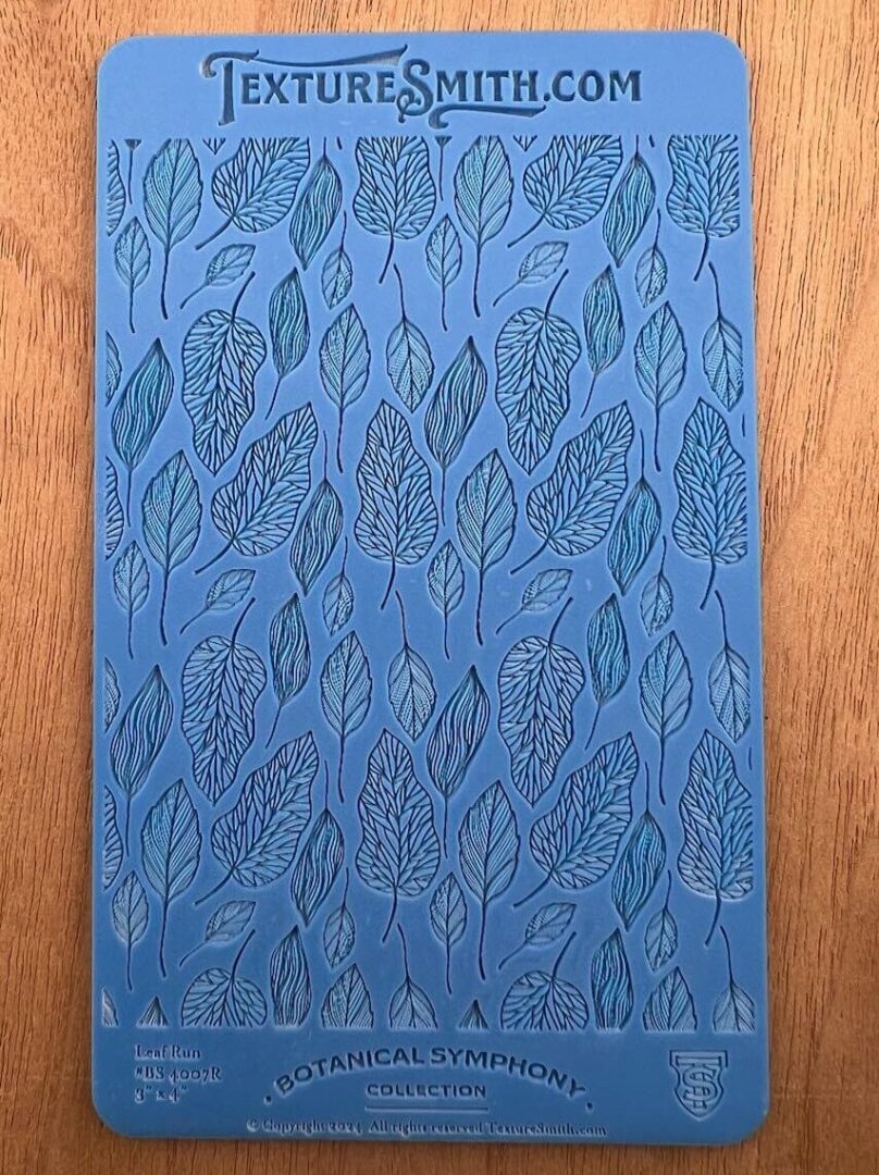Blue notebook with a leaf pattern on a wooden surface.