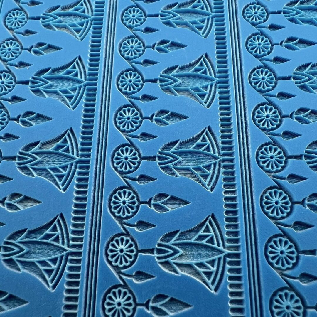 Close-up of blue fabric with intricate black geometric and floral patterns.