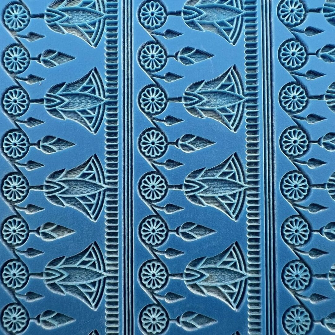 Blue fabric with intricate geometric and floral patterns in repeating vertical strips.