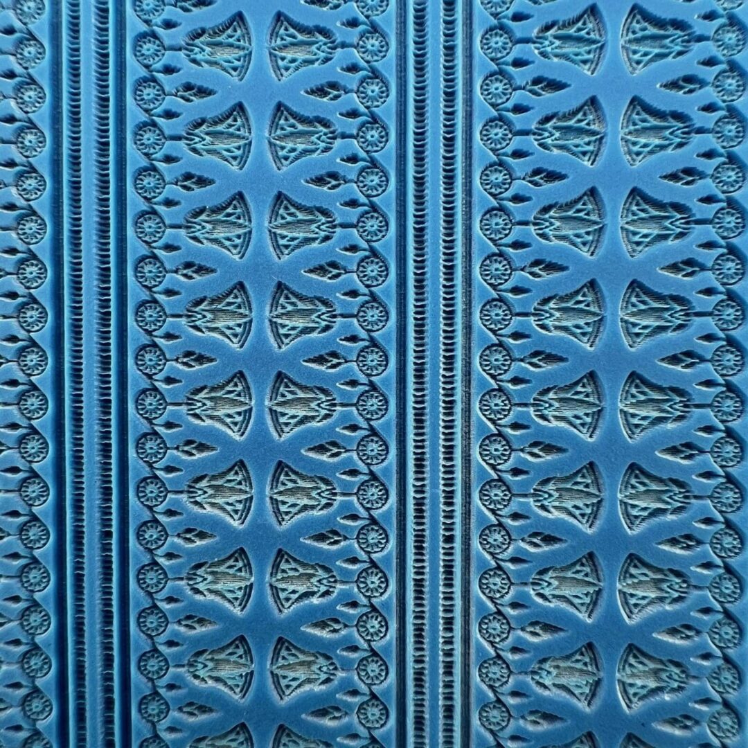 Close-up of intricate blue fabric with patterned embroidery.