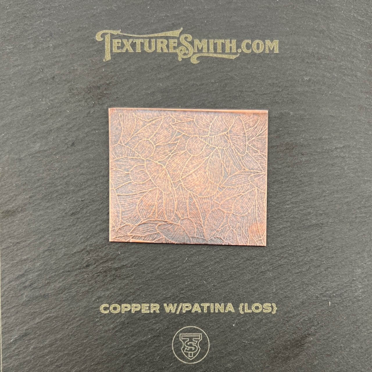 A copper sheet with a patina finish on a textured background.