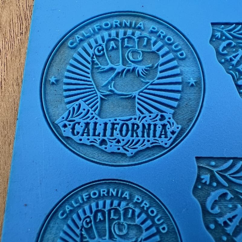 Embossed California-themed designs with a raised fist and rays on blue material.