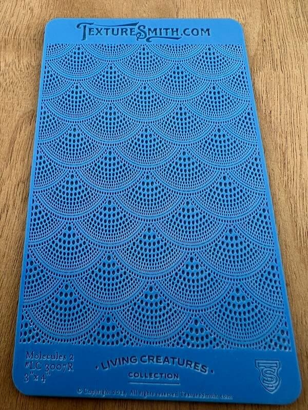 Blue textured mat with a repeating fan-like pattern on wooden floor.