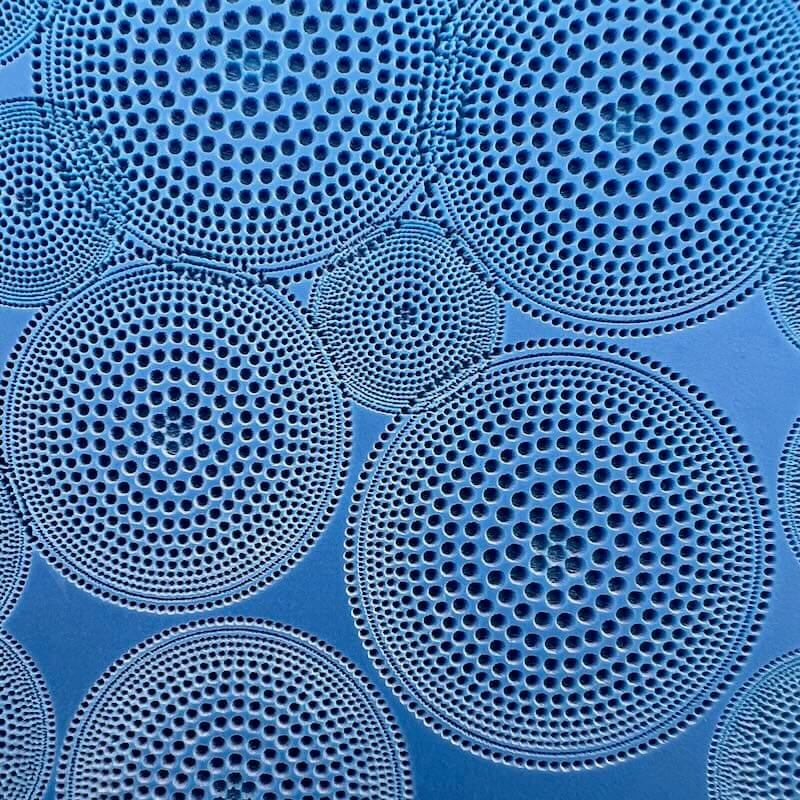 Close-up of circular, perforated metal plates with a blue background.