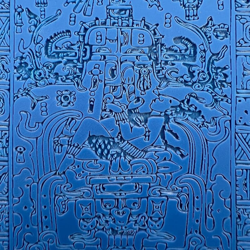 Intricate blue embossed artwork with detailed mythical and animal figures.