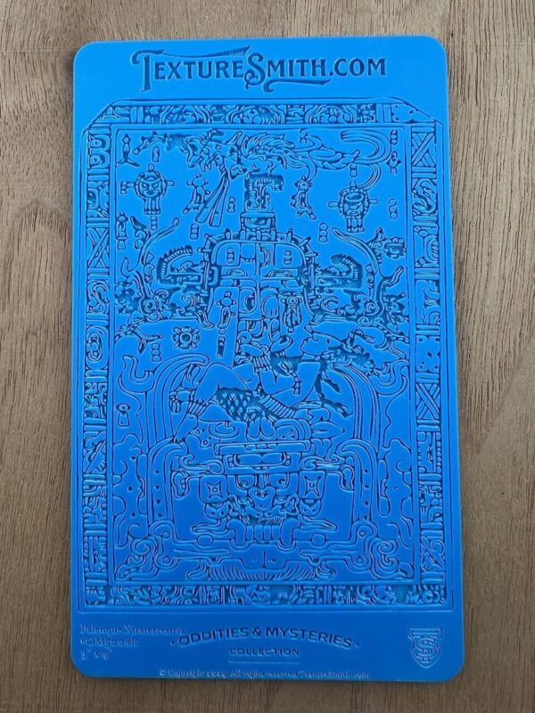 Intricate blue embossed artwork with various detailed figures and patterns.