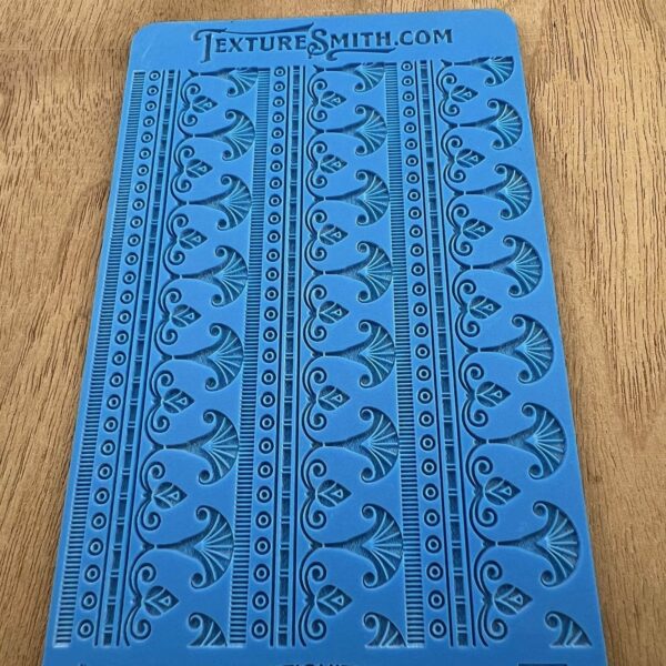 Blue stencil with floral and geometric patterns on a wooden surface.