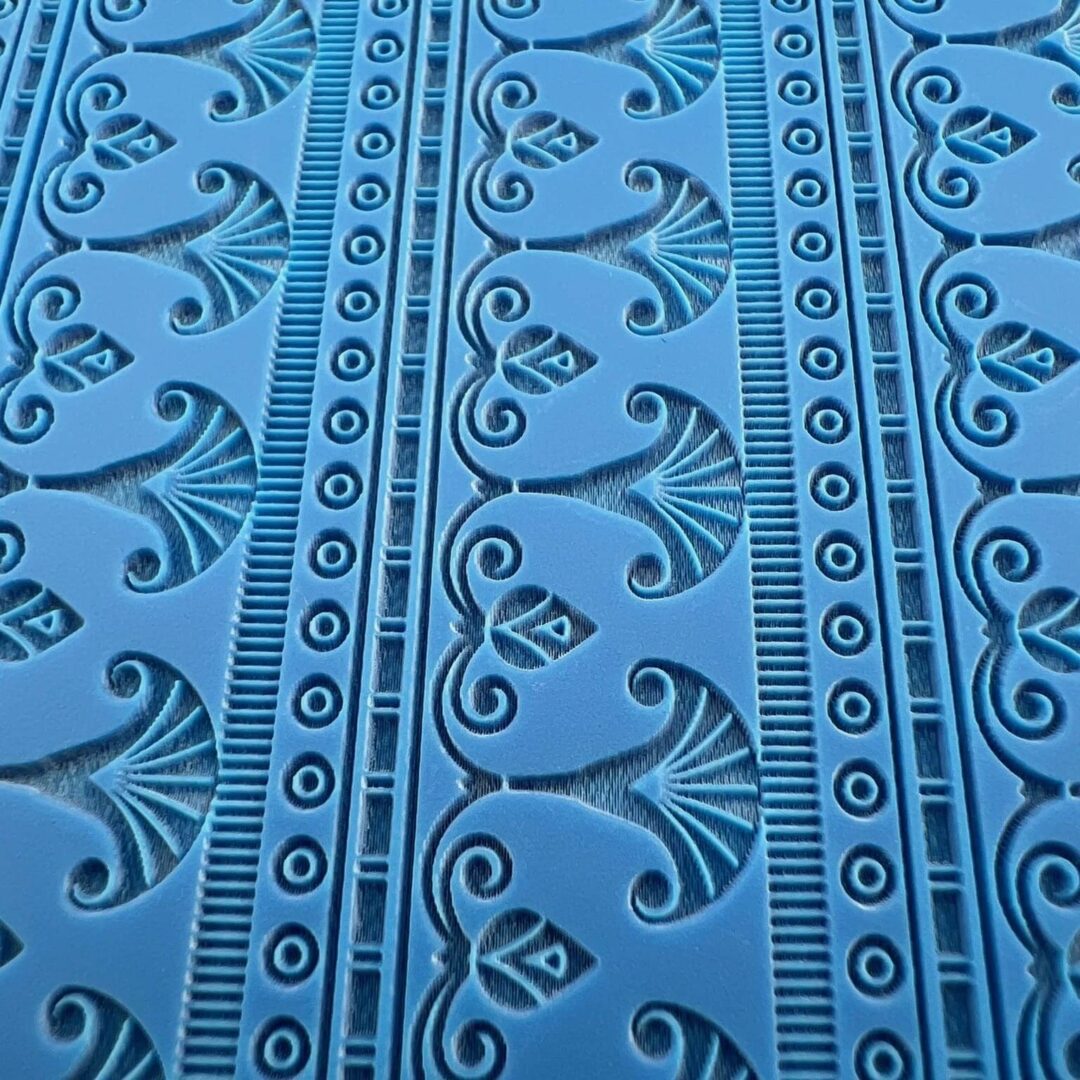 Blue fabric with intricate black floral and geometric patterns.