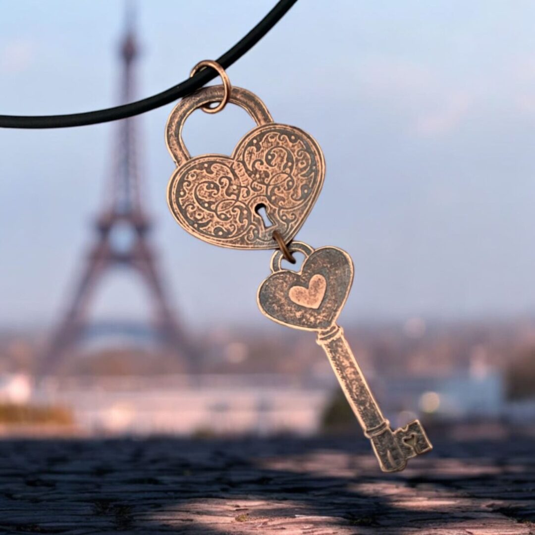 Heart-shaped key pendant with Eiffel Tower blurred in background.