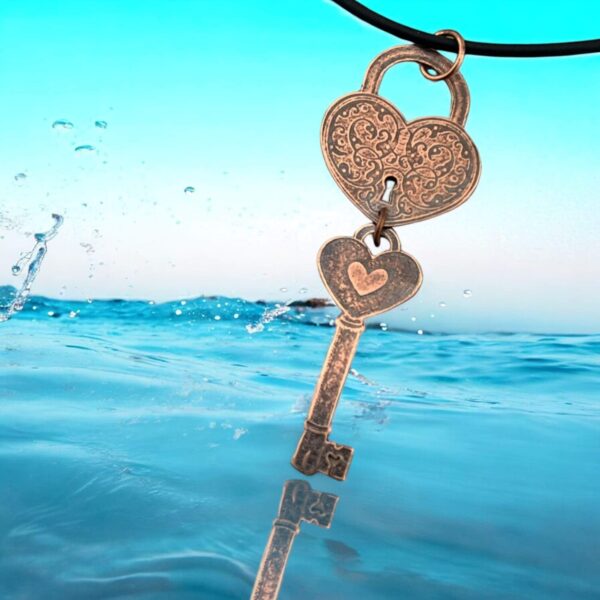 A heart-shaped key pendant hanging over water with a splash.