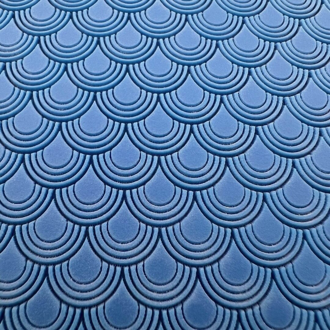 Blue fabric with a repeating scallop pattern.