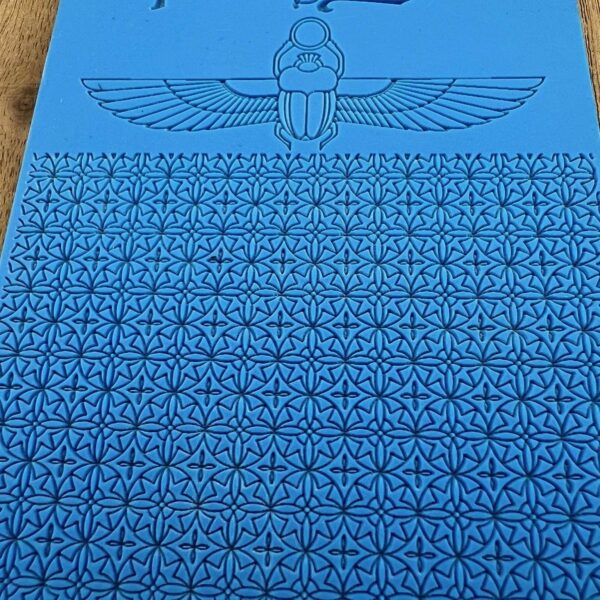 A blue sheet with repeated swastika patterns and a winged symbol at the top.