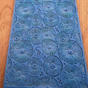 Blue textured fabric with circular floral patterns on a wooden surface.