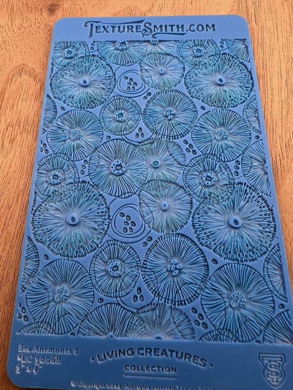 Blue textured fabric with circular floral patterns on a wooden surface.