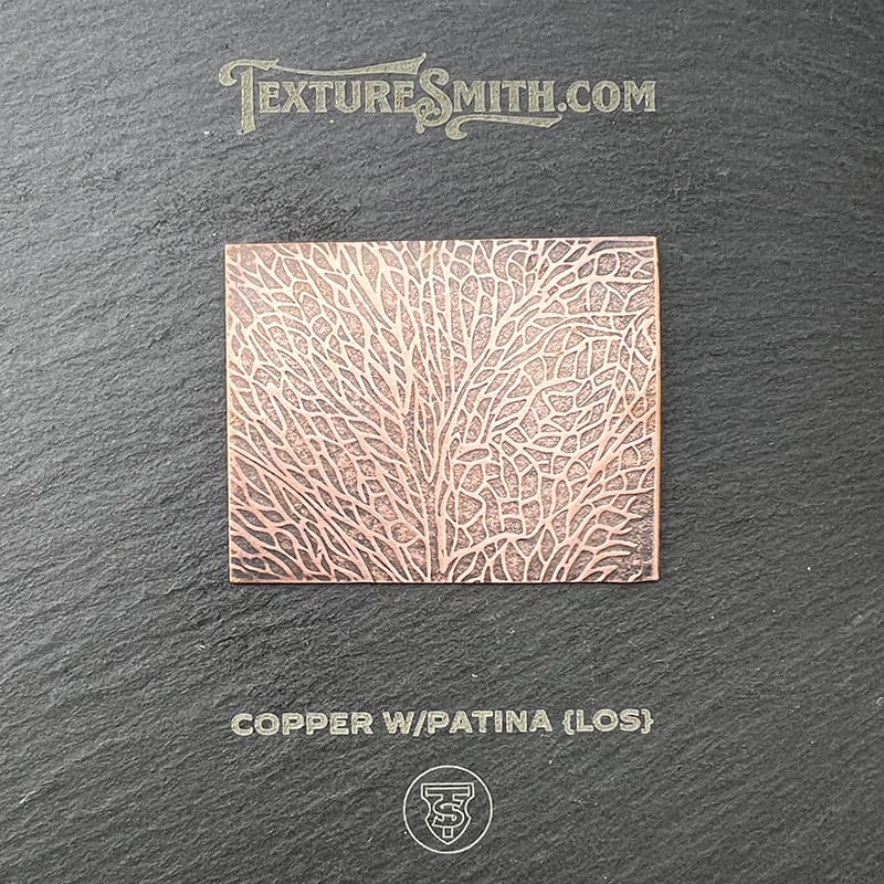 Close-up of copper surface with patina texture on a dark background.
