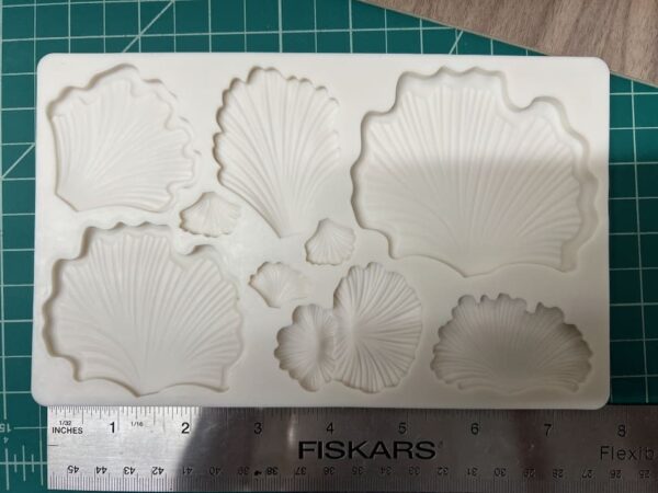 Various white clay or plaster shells and sea-themed shapes on a cutting mat.