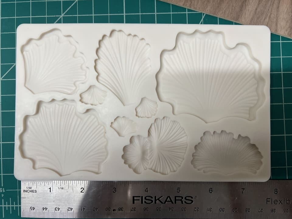Various white clay or plaster shells and sea-themed shapes on a cutting mat.