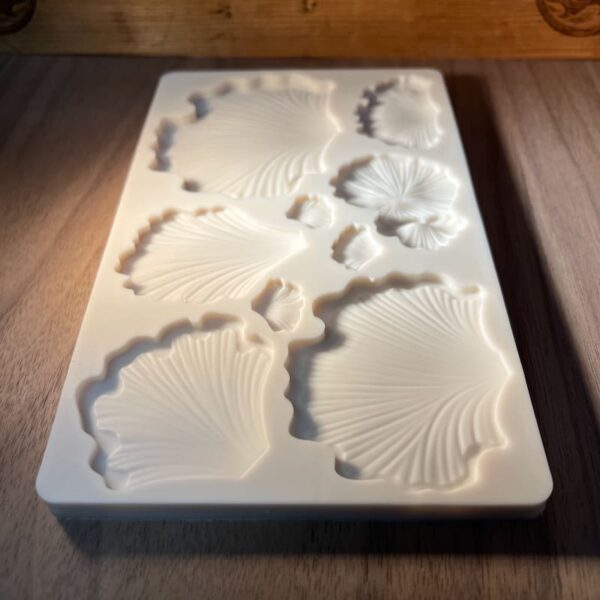 A silicone mold with various seashell shapes on a wooden surface.
