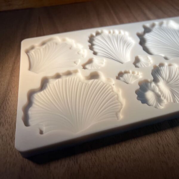 A white mold with various sea shell shapes on a wooden surface.