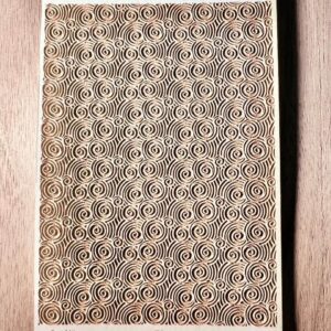 Intricate rectangular mat with repeating geometric patterns on a wooden surface.