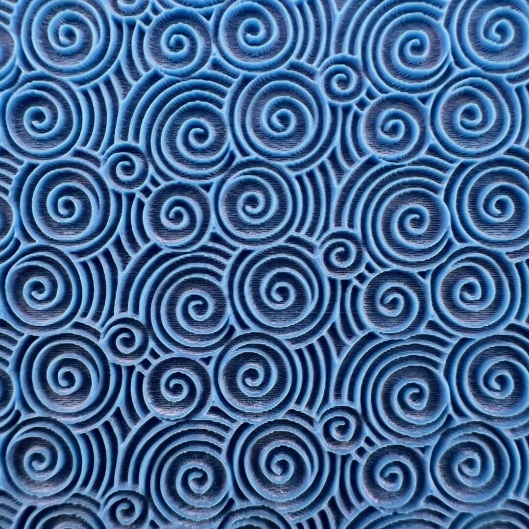 Blue fabric with intricate black spiral patterns.