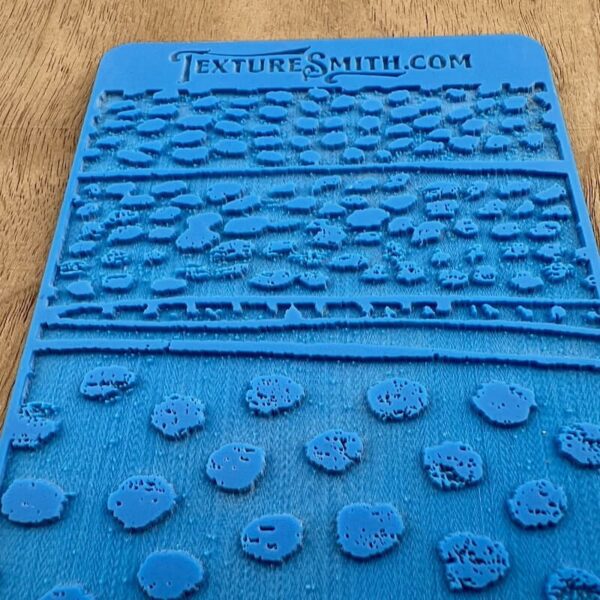 Blue textured silicone mat with various patterns and the website text.