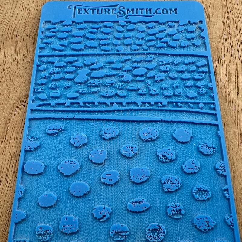 Blue textured silicone soap mold with various shapes.