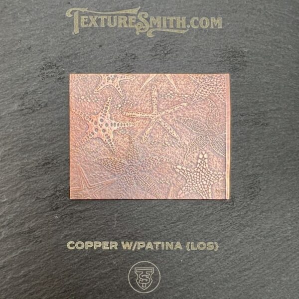 Copper patina tile with floral design on dark background.