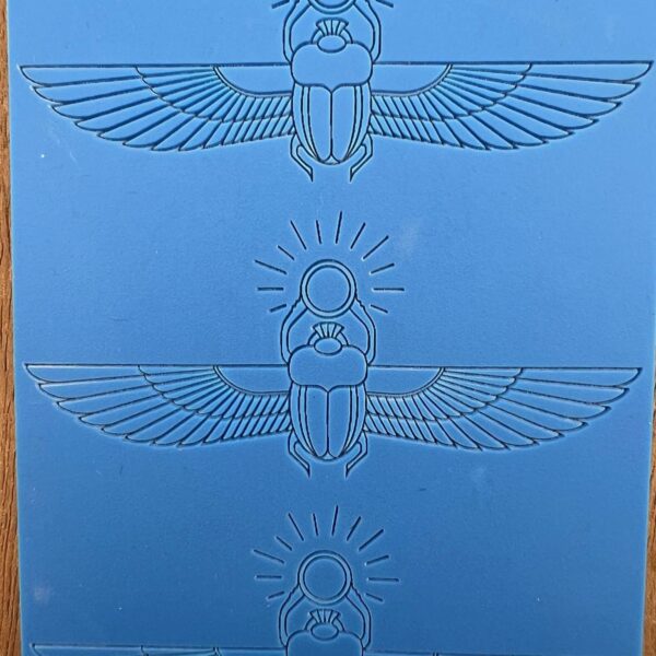 Three blue embossed Egyptian scarab designs with wings on a blue background.