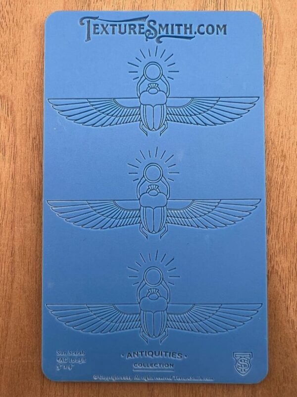 Blue card with three embossed Egyptian scarab designs.
