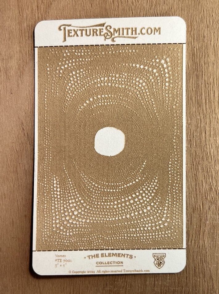 Abstract artwork featuring a central white circle surrounded by intricate, swirling gold patterns on a beige background.