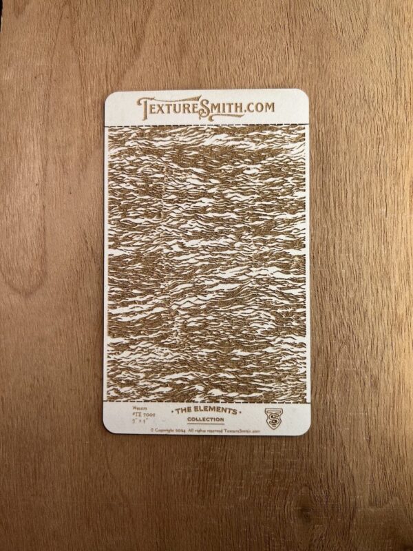 Vintage textured card with intricate brown and white pattern on wood surface.