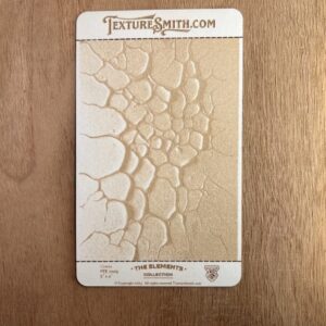 Textured stamp creating cracked earth pattern on clay.