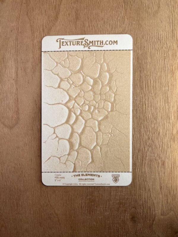 Textured stamp creating cracked earth pattern on clay.