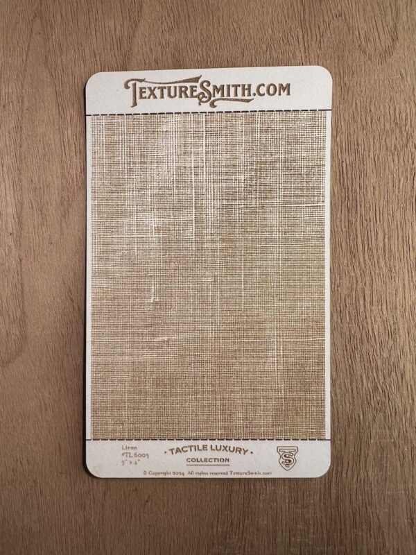 A textured fabric sample card from TextureSmith.com laid on wood.